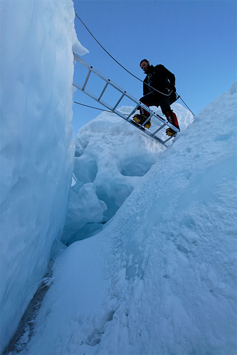 Andy climbs a ladder in the icefall